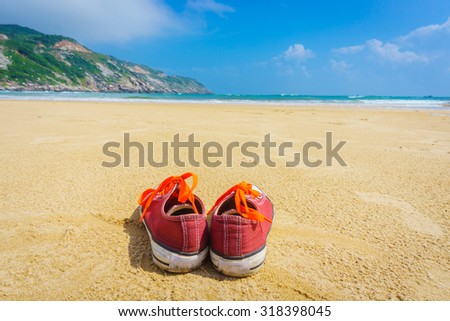 The Orange shoes sit on a sandy beach
