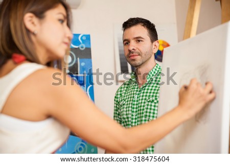 Young female artist drawing a portrait of an attractive male model in her studio
