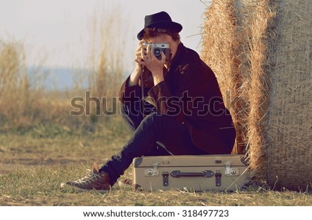 Young man photographing traveler on the road with old suitcases