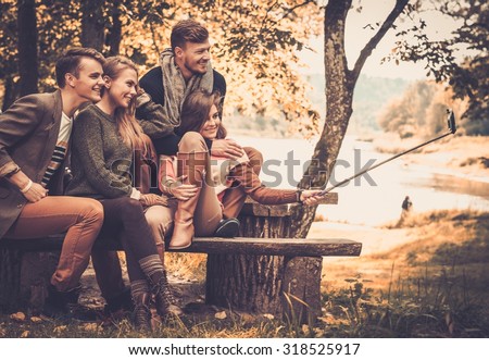 Cheerful friends in autumn park taking selfie