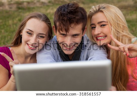 Three friends watching taking pictures with tablet pc in park