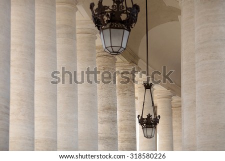 Closeup view on street lams hanging on ceiling in terrace of building with many long big columns in row from beautiful white stone outdoor colonnade, horizontal picture