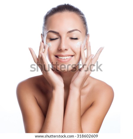 beautiful model applying cosmetic cream treatment on her face on white Royalty-Free Stock Photo #318602609