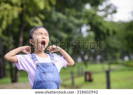 Little girl yawning in the green garden 