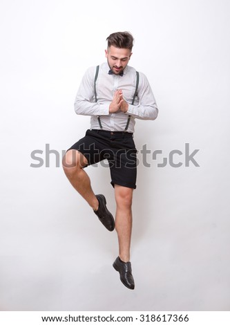 Hipster man clasped his hands for praying over white background. Man jumping and looking down in photo studio.