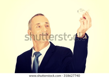 Portrait of businessman holding small airplane.