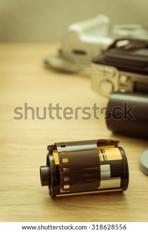 photo film in cartridge and film camera on wooden table.