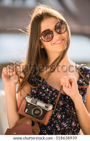 Beautiful woman is having fun with old fashioned camera. Summer, outdoors.