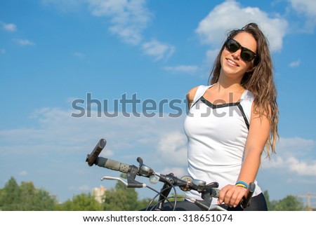 Young woman with a bike in a summer park.