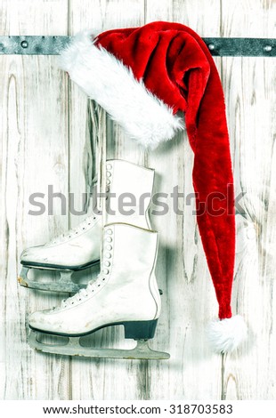 Christmas decoration. Red Santa's hat and white ice skates hanging on wooden background