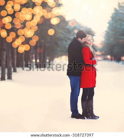 Silhouette of loving couple embracing in warm winter day with festive bokeh

