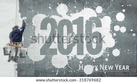Building painter hanging from harness painting a wall with the words Happy New Year 2016