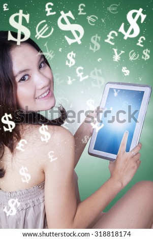 Photo of a beautiful teenage girl smiling at the camera while holding a digital tablet for making money online