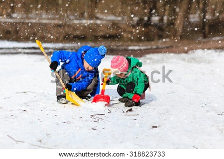 little boy and girl digging snow in winter, kids winter activities