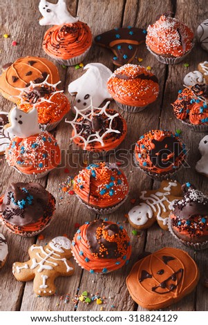 Traditional Halloween cupcakes and gingerbread cookies close-up on the table. vertical background
