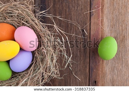 colorful pink purple and yellow eggs with hay vintage white and blue wood background