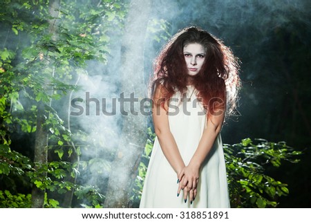 Girl in witch costume for Halloween in a forest. Beautiful zombie bride in halloween. Zombie girl.