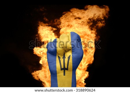 fist with the national flag of barbados near the fire on a black background