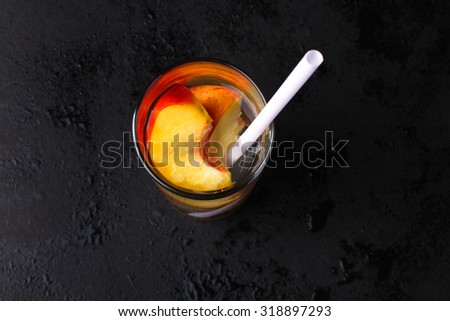 slices of peach in a glass of water on black background