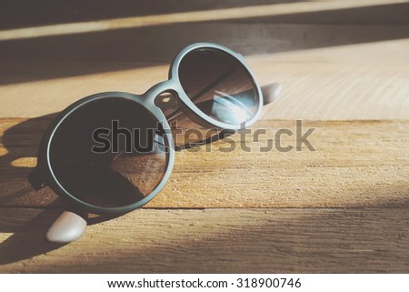 Sunglasses with shadow on wooden background. Close up. Toned image.