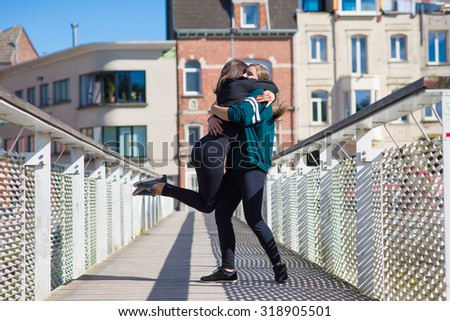 Two girls hugging intensely on a bridge