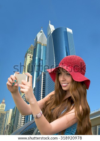 Girl in a red hat is taking a selfie in front of skyscrapers in Dubai. Cityscape, view of skyscrapers, Dubai