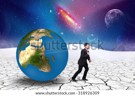 Businessman pulls world sphere in cosmos desert .Elements of this image furnished by NASA