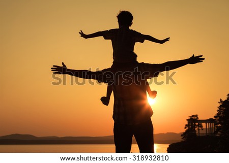father and son playing on the coast of lake in the mountains of at the sunset time