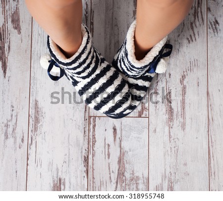 Warm slippers on the background old white floor. Homeliness. 