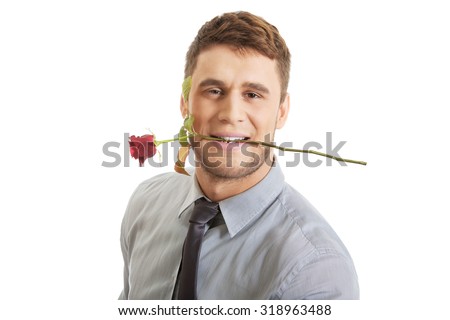 Young handsome man holding red rose in his mouth. Royalty-Free Stock Photo #318963488