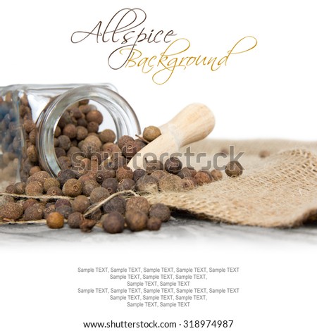 Photo of glass spicebox full of allspice on burlap with white space
