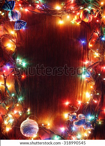 Christmas garlands of lamps on a wooden background. Frame of Christmas lights