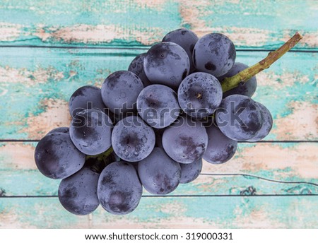 A bunch of black grapes over wooden background