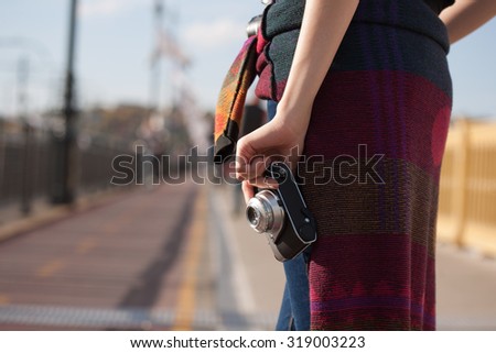 Young photographer strolling the sunlit city streets with her camera.