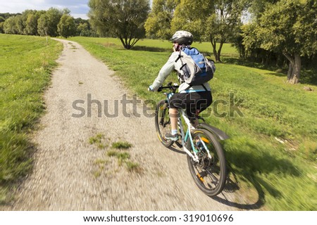 Woman bicyclists riding on country road. Natural motion blur.