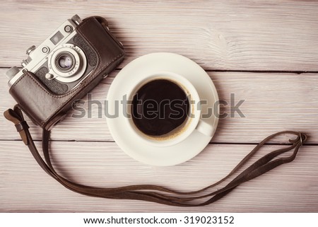 Vintage camera and cup of coffee on old wooden table