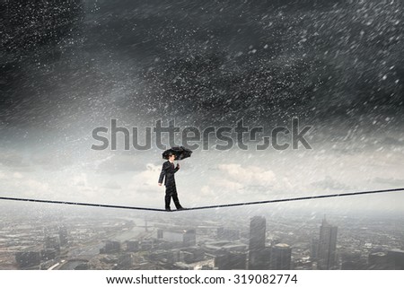 Businessman with umbrella balancing on rope high on sky Royalty-Free Stock Photo #319082774