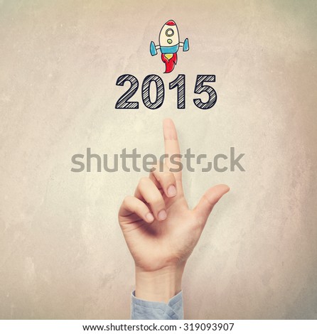 Hand pointing to 2015 concept on light brown wall background