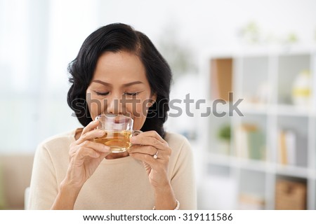 Mature Asian woman drinking hot herbal tea