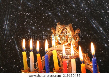Image of jewish holiday Hanukkah background with menorah (traditional candelabra) Burning candles over black background with glitter overlay
