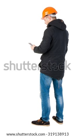 Backview of an engineer in construction helmet stands and using a mobile phone. Standing young guy. Rear view people collection.  backside view of person.  Isolated over white background.