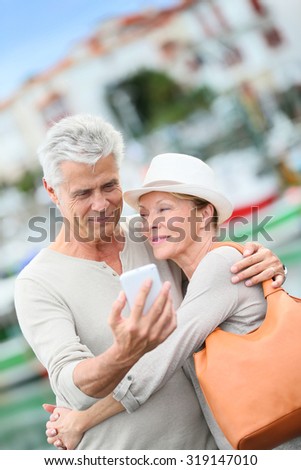 Senior couple of tourists taking picture with smartphone