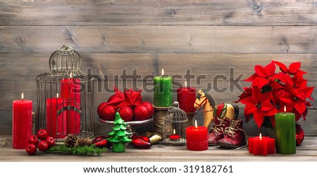 vintage christmas decoration with burning candles, antique baby shoes, red flower poinsettia, stars and baubles. Retro style toned picture