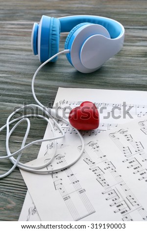 Earphones with red heart and music notes on wooden table close up