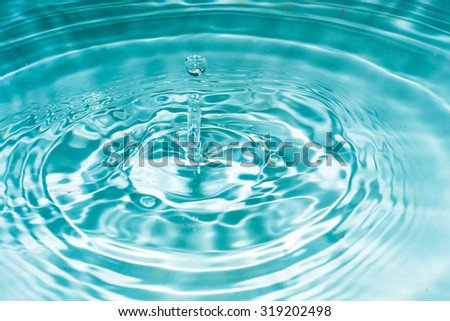 Water drop falling into the water. Royalty-Free Stock Photo #319202498