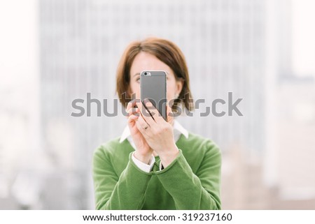 Woman taking a selfie with a smartphone in an urban business background