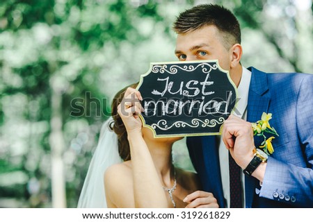 Bride and groom holding "Just married" sign. Wedding day