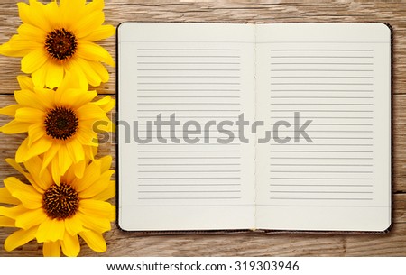 Diary and ornamental sunflowers on wooden background