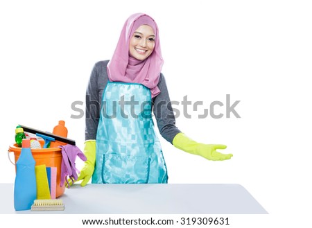 portrait of young woman wearing hijab presenting clean table with cleaning equipment isolated on white with copy space