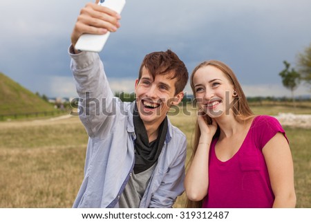 Two friends with mobile phone taking selfies.  Summer time
